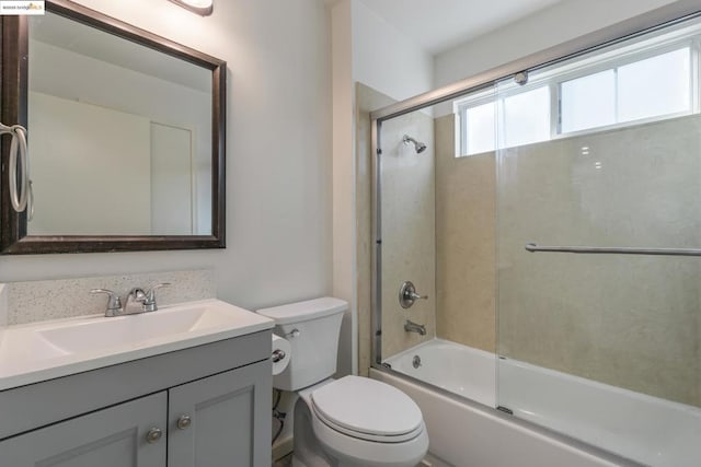 full bathroom featuring vanity, bath / shower combo with glass door, and toilet