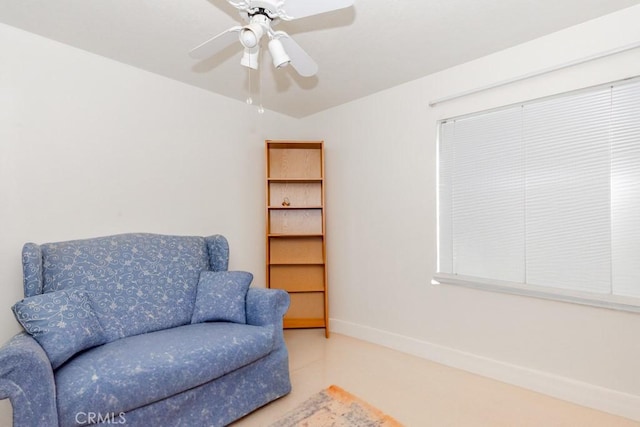 living area featuring baseboards and a ceiling fan