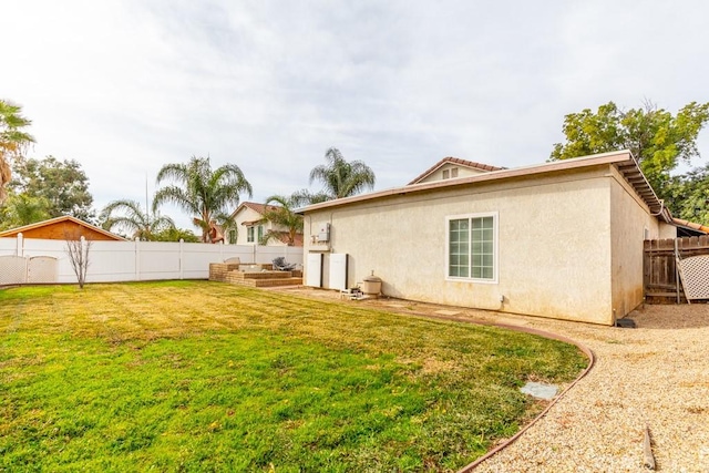 back of house featuring a fenced backyard, a lawn, and stucco siding