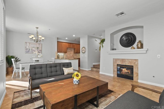 living room with a chandelier, sink, a tile fireplace, and light tile patterned floors