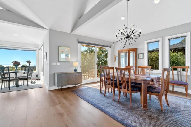 dining room featuring an inviting chandelier, hardwood / wood-style floors, a wealth of natural light, and vaulted ceiling