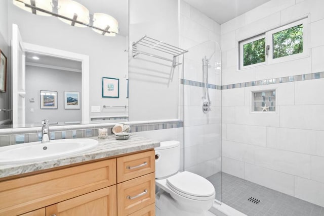 bathroom featuring vanity, toilet, tile walls, and a tile shower