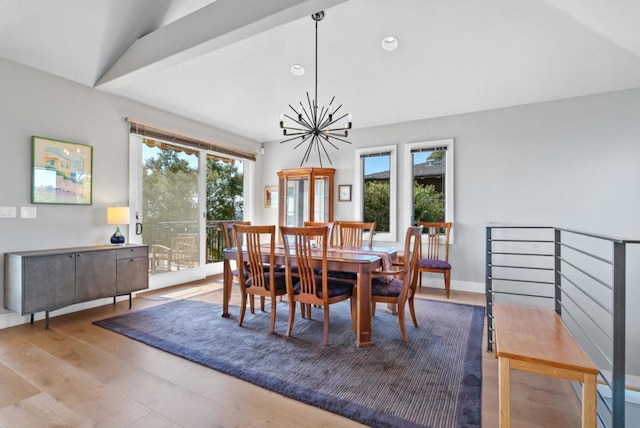 dining area featuring a chandelier, vaulted ceiling, and light wood-type flooring