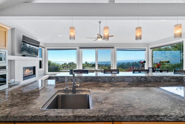 kitchen featuring pendant lighting, sink, oven, and dark stone countertops