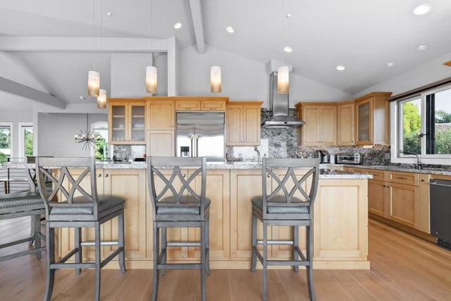 kitchen with stainless steel built in refrigerator, decorative light fixtures, a center island, light stone countertops, and wall chimney range hood