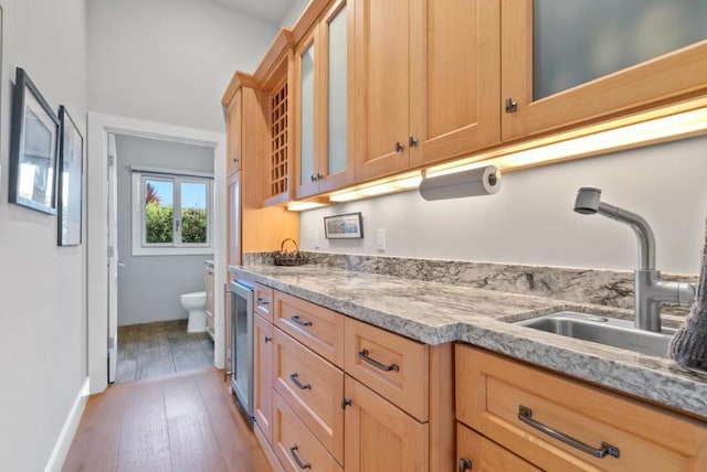 kitchen with wine cooler, wood-type flooring, sink, and light stone counters