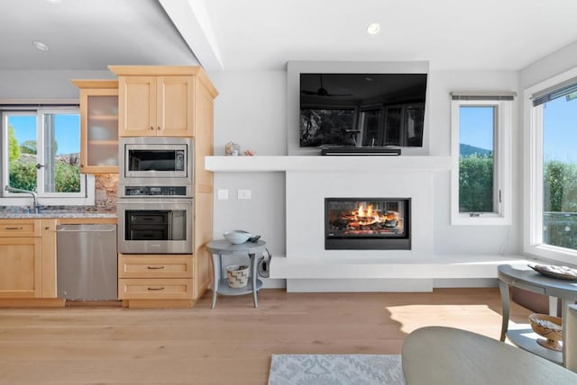 kitchen with plenty of natural light, stainless steel appliances, light hardwood / wood-style floors, and light brown cabinets