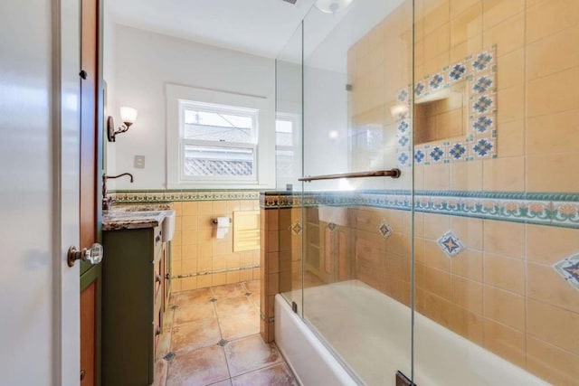 bathroom with tile walls, vanity, tile patterned flooring, and bath / shower combo with glass door