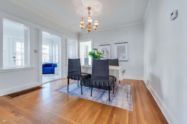 dining space with a notable chandelier, hardwood / wood-style flooring, and ornamental molding