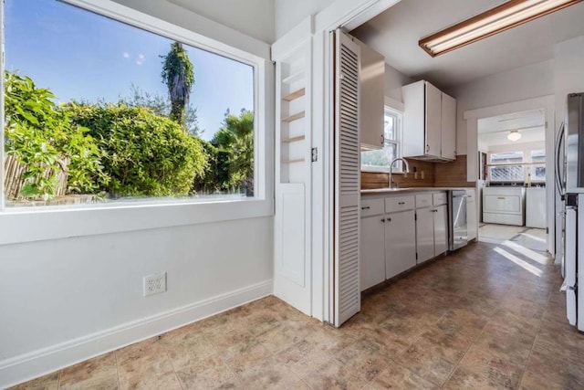 kitchen with white cabinetry, sink, decorative backsplash, stainless steel dishwasher, and washer and clothes dryer