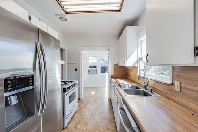 kitchen with dishwasher, white cabinetry, sink, stainless steel fridge, and white range with gas stovetop