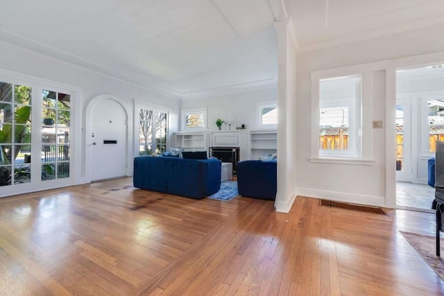 unfurnished living room featuring ornamental molding, a healthy amount of sunlight, and light hardwood / wood-style flooring