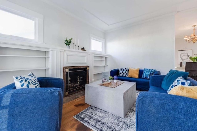 living room with an inviting chandelier, ornamental molding, dark hardwood / wood-style floors, and built in shelves