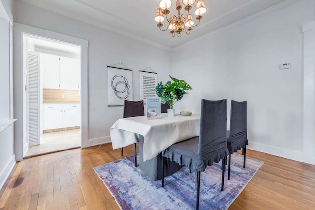 dining space featuring ornamental molding, a chandelier, and light hardwood / wood-style floors