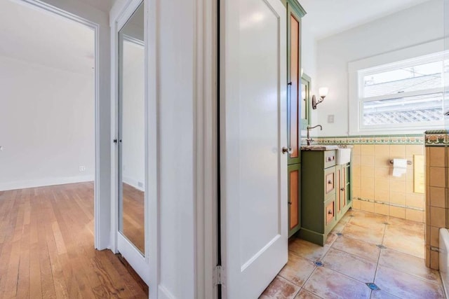 corridor featuring tile walls and light hardwood / wood-style floors