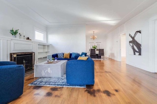 living room featuring an inviting chandelier, ornamental molding, wood-type flooring, and built in features