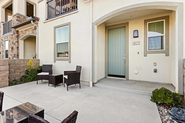 view of exterior entry with an outdoor living space and a patio