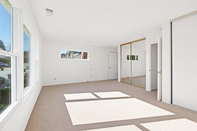 unfurnished bedroom featuring light colored carpet and multiple closets