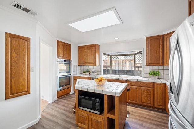 kitchen with tasteful backsplash, tile counters, a center island, and appliances with stainless steel finishes