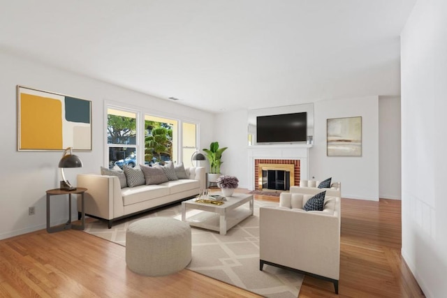 living room with a brick fireplace and light wood-type flooring