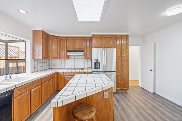 kitchen with sink, crown molding, a center island, black appliances, and tile countertops