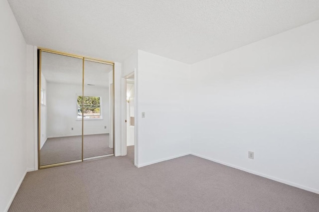 unfurnished bedroom featuring carpet flooring, a textured ceiling, and a closet