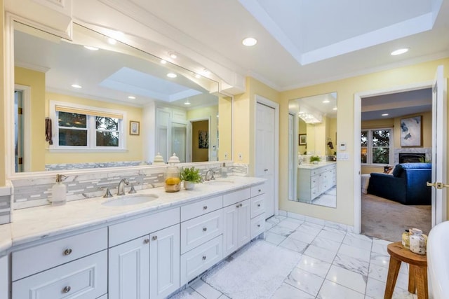 bathroom featuring a raised ceiling, tasteful backsplash, vanity, and crown molding