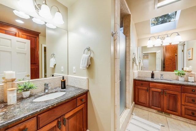 bathroom with a skylight, vanity, an enclosed shower, and tile patterned floors