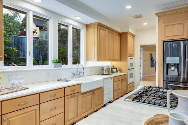 kitchen with stainless steel appliances, light brown cabinetry, and sink