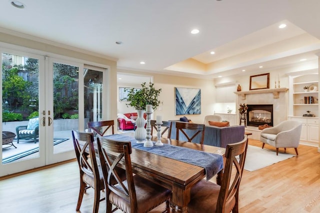 dining room featuring french doors, crown molding, a raised ceiling, and light hardwood / wood-style flooring