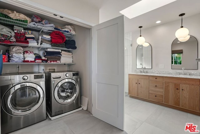 laundry area featuring sink, light tile patterned floors, washer and clothes dryer, and a skylight