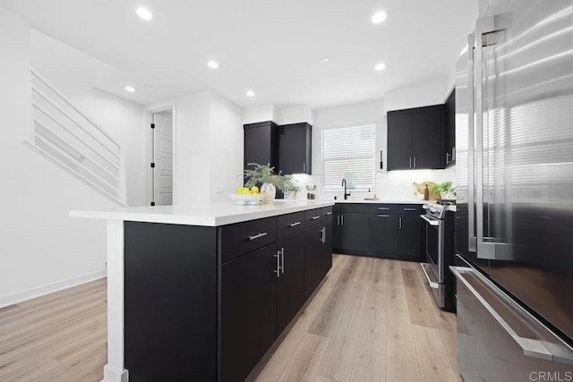 kitchen with stainless steel appliances, a center island, sink, and light wood-type flooring