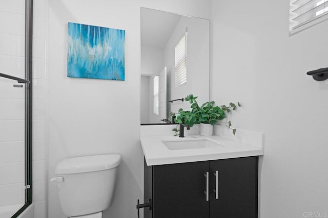 full bathroom featuring vanity, combined bath / shower with glass door, and toilet