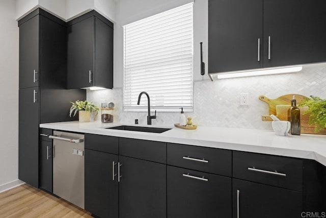 kitchen with stainless steel dishwasher, light hardwood / wood-style floors, and sink