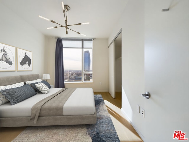 bedroom with wood-type flooring and an inviting chandelier