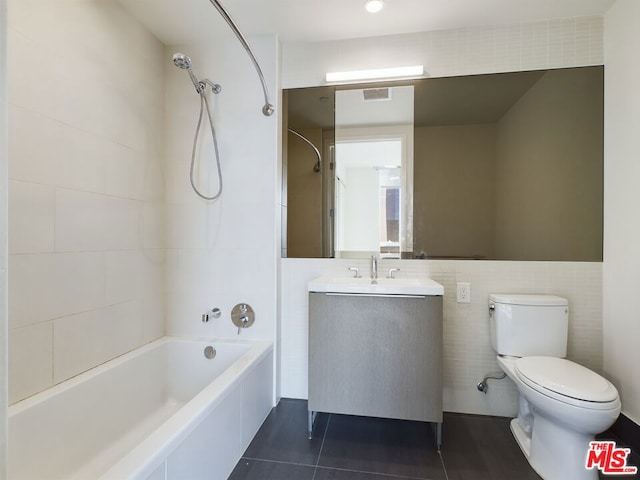 full bathroom featuring washtub / shower combination, toilet, tile walls, vanity, and tile patterned flooring