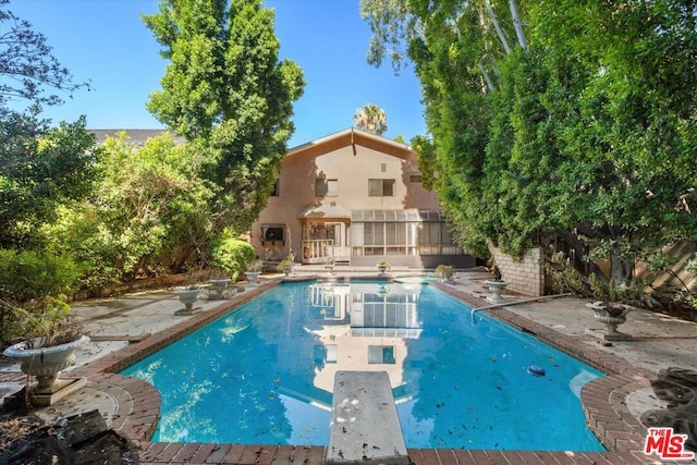 view of swimming pool featuring a patio and a diving board