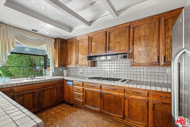 kitchen with stainless steel appliances, tile counters, ventilation hood, parquet floors, and decorative backsplash