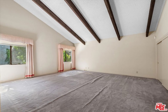 spare room with beamed ceiling, carpet, and high vaulted ceiling