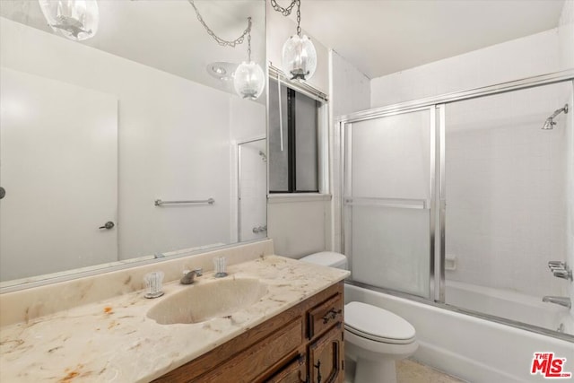 full bathroom featuring vanity, shower / bath combination with glass door, and toilet