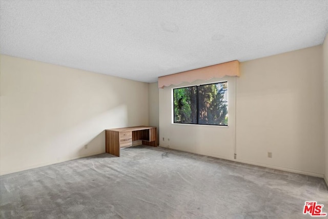 carpeted empty room with a textured ceiling