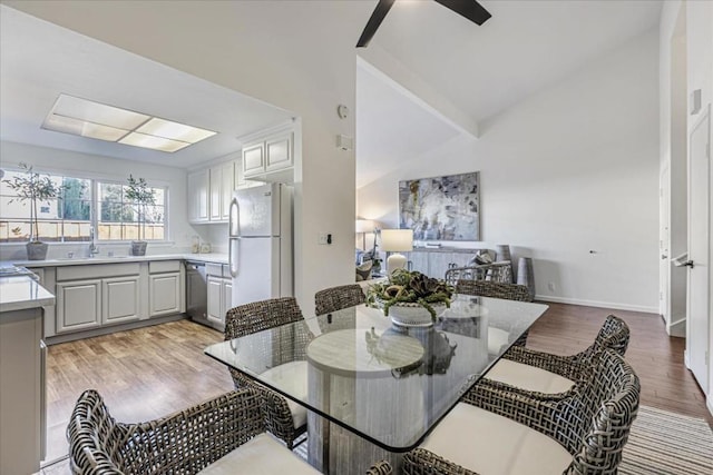 dining room featuring lofted ceiling, sink, ceiling fan, and light hardwood / wood-style flooring