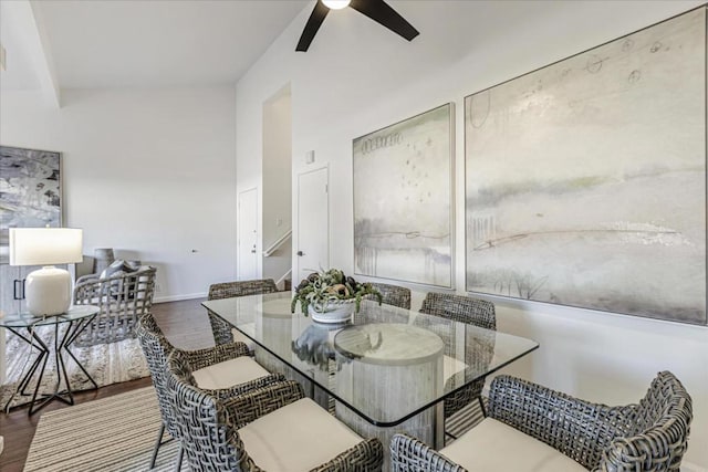 dining space with wood-type flooring, beamed ceiling, and ceiling fan