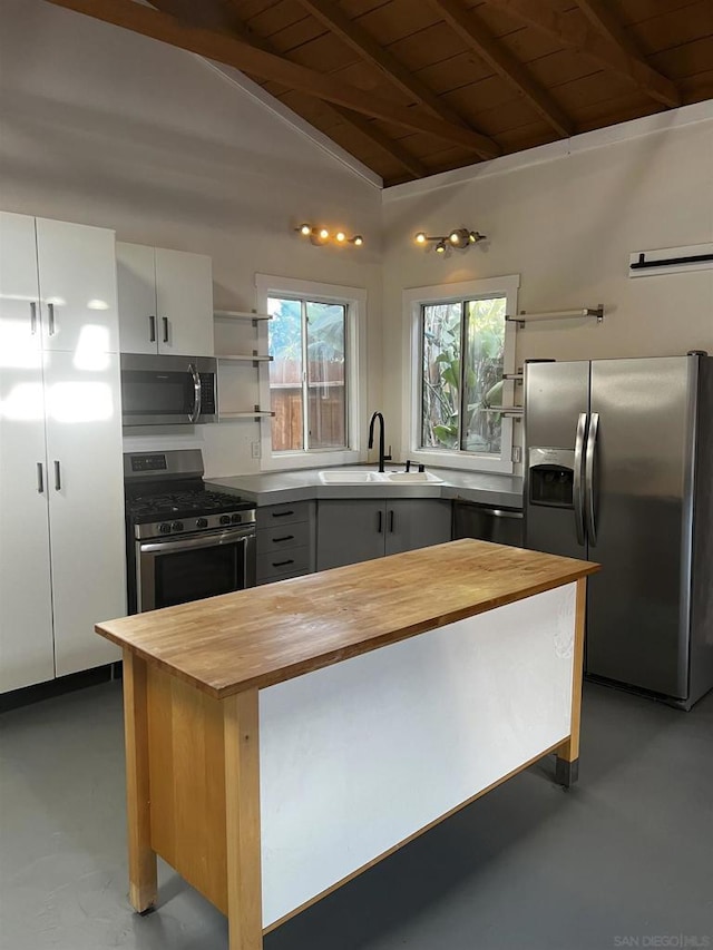 kitchen featuring appliances with stainless steel finishes, vaulted ceiling with beams, white cabinets, wooden counters, and wooden ceiling