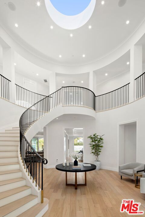 foyer entrance featuring crown molding, light hardwood / wood-style flooring, and a high ceiling