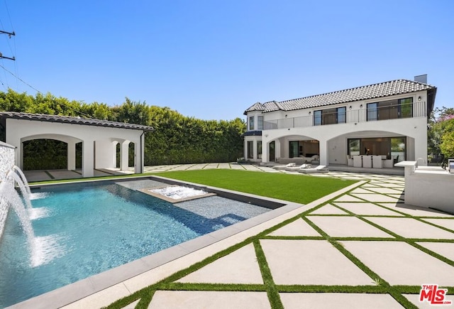 back of house with a balcony, a lawn, pool water feature, and a patio area