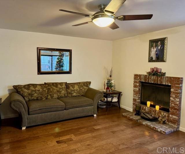 living room with hardwood / wood-style flooring, a brick fireplace, and ceiling fan