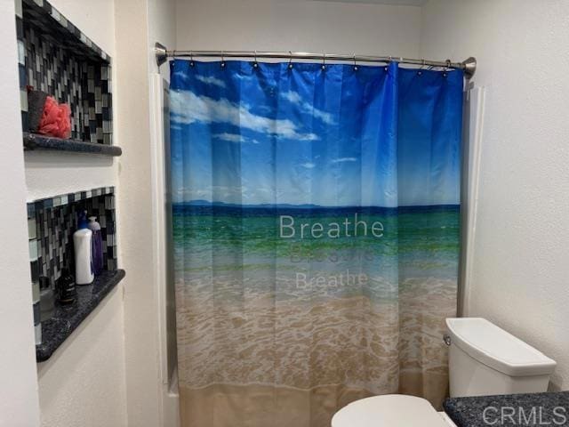 bathroom with curtained shower and toilet