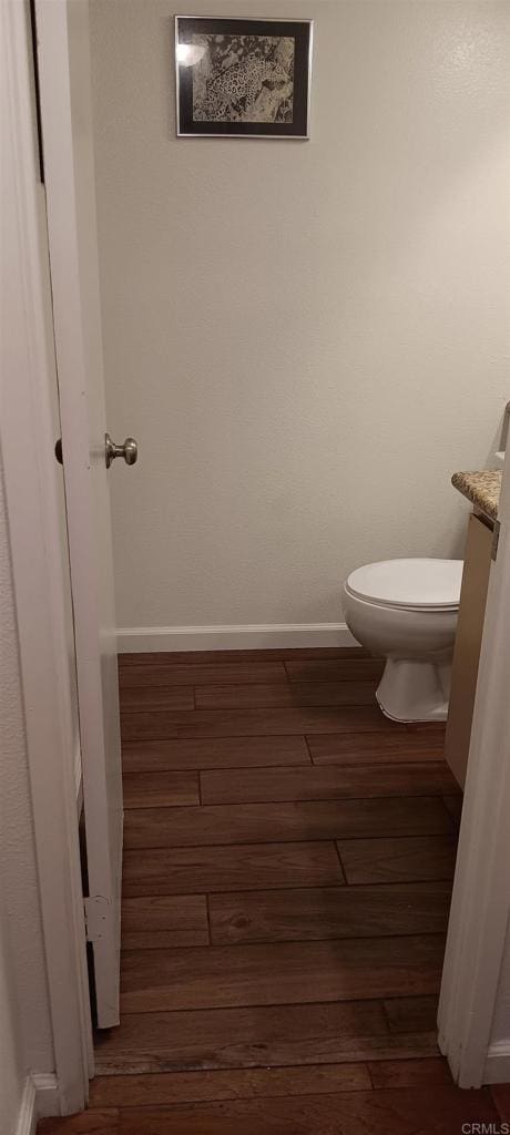 bathroom with toilet, baseboards, and wood finished floors