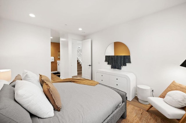 bedroom featuring connected bathroom and light hardwood / wood-style flooring